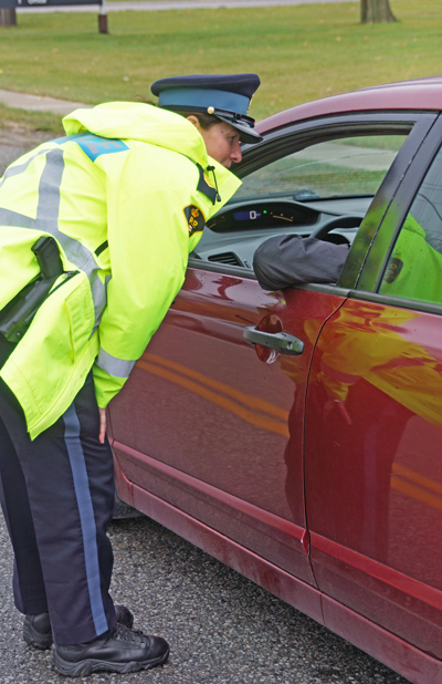 Police officer leaning down to a car window. 