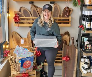 Smiling woman holds a showbox wrapped in Christmas wrapping paper.